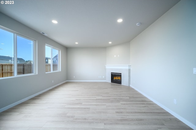 unfurnished living room with a fireplace, recessed lighting, visible vents, light wood-style flooring, and baseboards