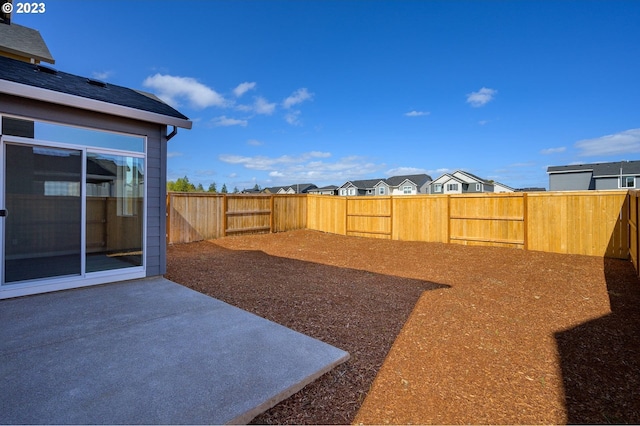 view of yard featuring a patio, a fenced backyard, and a residential view