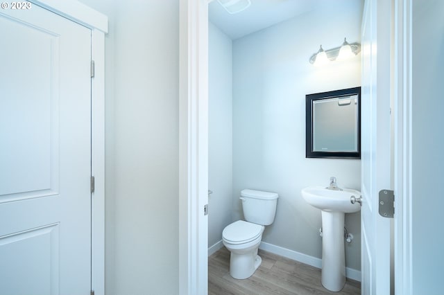 bathroom featuring toilet, a sink, baseboards, and wood finished floors