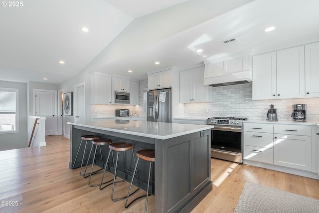 2150 NW Inlet Ave, Lincoln City, OR 97367 - kitchen with visible vents, white cabinets, appliances with stainless steel finishes, a kitchen breakfast bar, and light wood finished floors