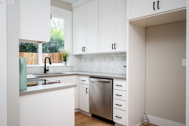 kitchen featuring tasteful backsplash, white cabinetry, dishwasher, sink, and light hardwood / wood-style flooring