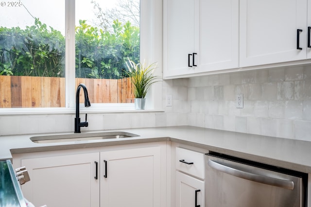 kitchen featuring tasteful backsplash, dishwasher, sink, white cabinets, and range