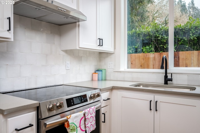 kitchen featuring stainless steel electric stove, sink, decorative backsplash, and white cabinets