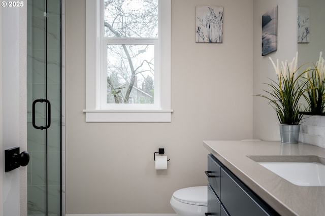 bathroom featuring a healthy amount of sunlight, toilet, a shower with shower door, and vanity