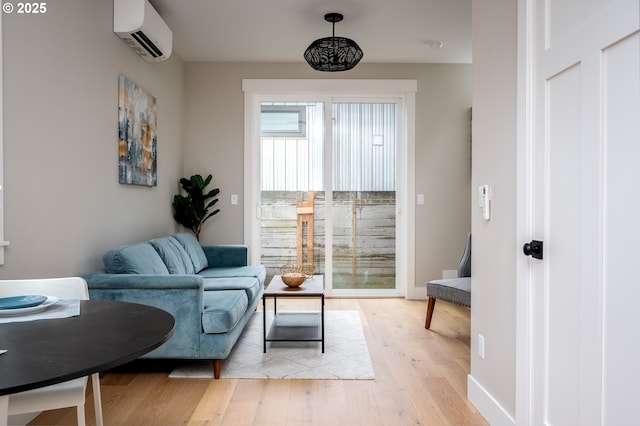 living area with a wall mounted air conditioner and light hardwood / wood-style flooring