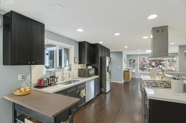 1842 SW Lobelia St, Portland, OR 97219 - kitchen with stainless steel appliances, island exhaust hood, dark cabinets, light countertops, and dark wood-type flooring