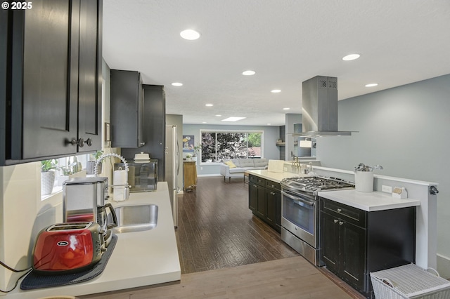 1842 SW Lobelia St, Portland, OR 97219 - kitchen with stainless steel gas stove, island exhaust hood, dark wood-style flooring, dark cabinets, and light countertops
