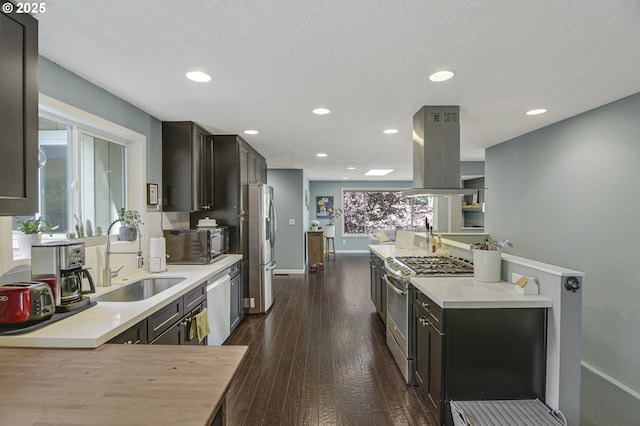 1842 SW Lobelia St, Portland, OR 97219 - kitchen featuring appliances with stainless steel finishes, island range hood, recessed lighting, light countertops, and dark wood-style floors