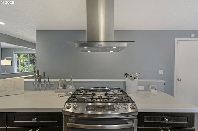 1842 SW Lobelia St, Portland, OR 97219 - kitchen featuring stainless steel range with gas stovetop, island exhaust hood, a textured ceiling, dark cabinets, and light countertops