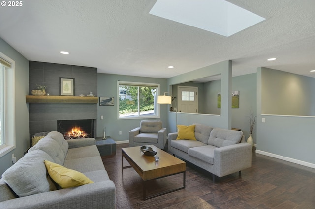 1842 SW Lobelia St, Portland, OR 97219 - living room with a textured ceiling, dark wood-type flooring, a tiled fireplace, a skylight, and recessed lighting