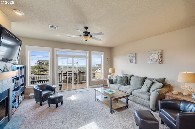 living area with carpet flooring, a fireplace, visible vents, and a healthy amount of sunlight