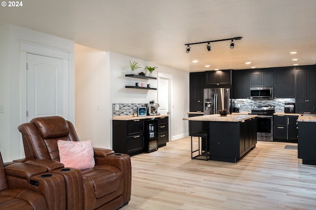 kitchen featuring decorative backsplash, appliances with stainless steel finishes, light wood-type flooring, a breakfast bar, and a kitchen island