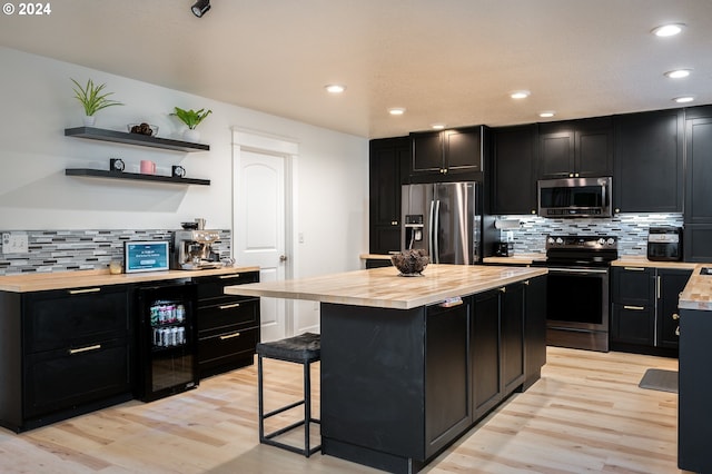 kitchen featuring wine cooler, light hardwood / wood-style floors, a breakfast bar area, and appliances with stainless steel finishes