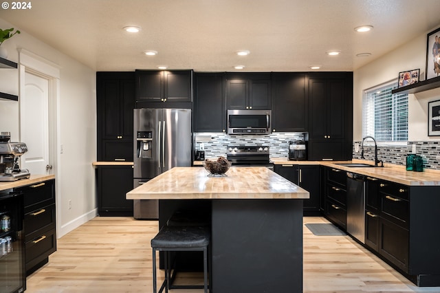 kitchen with sink, a center island, stainless steel appliances, a kitchen breakfast bar, and light hardwood / wood-style flooring