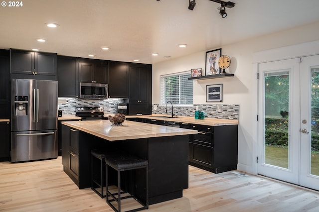 kitchen featuring a center island, sink, stainless steel appliances, light hardwood / wood-style flooring, and a breakfast bar area