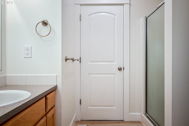 bathroom featuring vanity and a shower with door