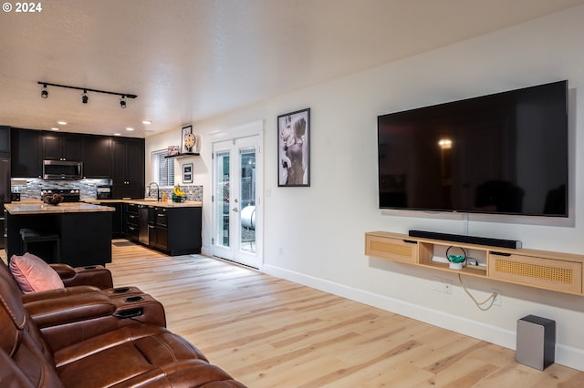 living room featuring french doors, light hardwood / wood-style flooring, and sink