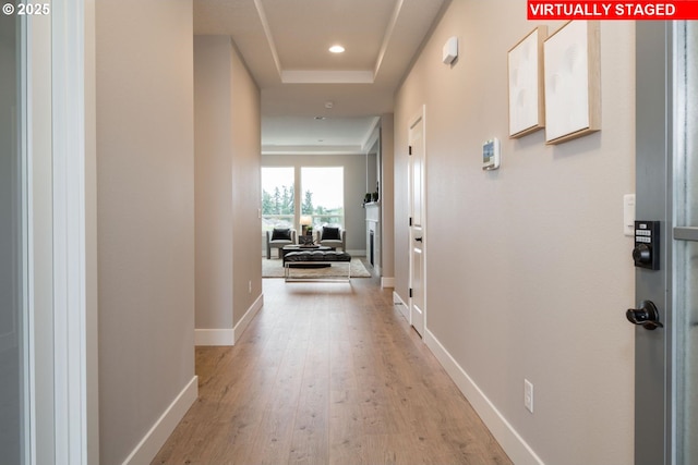 hallway featuring light hardwood / wood-style floors and a raised ceiling