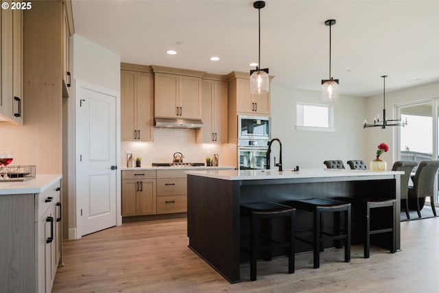 1303 S 46th Pl, Ridgefield, WA 98642 - kitchen with under cabinet range hood, appliances with stainless steel finishes, light countertops, backsplash, and healthy amount of natural light