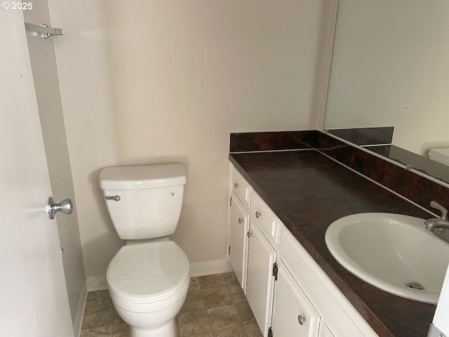 bathroom featuring baseboards, vanity, and toilet