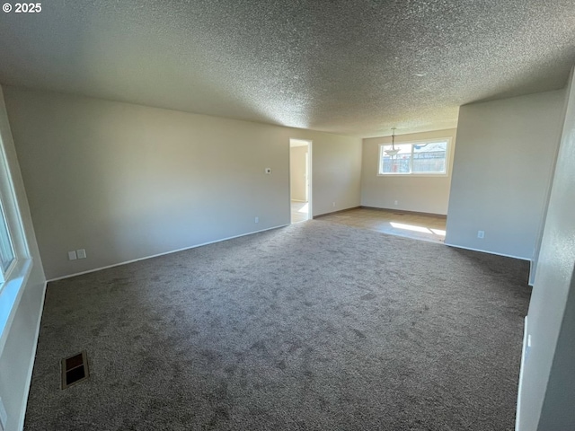 spare room featuring carpet floors, visible vents, and a textured ceiling