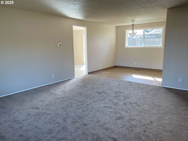 spare room with carpet floors, baseboards, and a textured ceiling