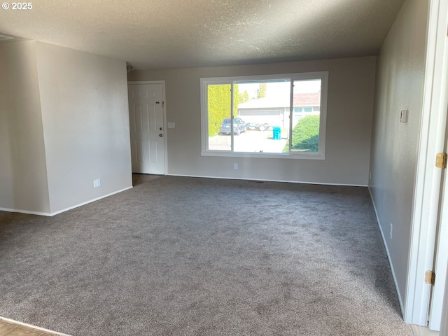 carpeted spare room featuring a textured ceiling and baseboards