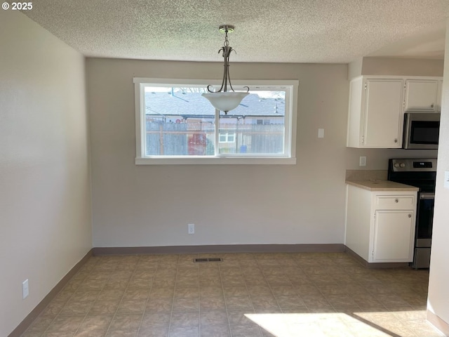 unfurnished dining area featuring a textured ceiling, visible vents, and baseboards