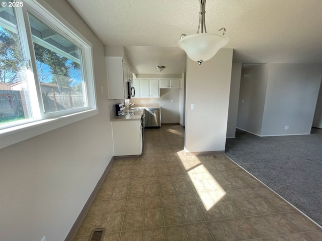 kitchen featuring visible vents, appliances with stainless steel finishes, dark carpet, decorative light fixtures, and white cabinetry