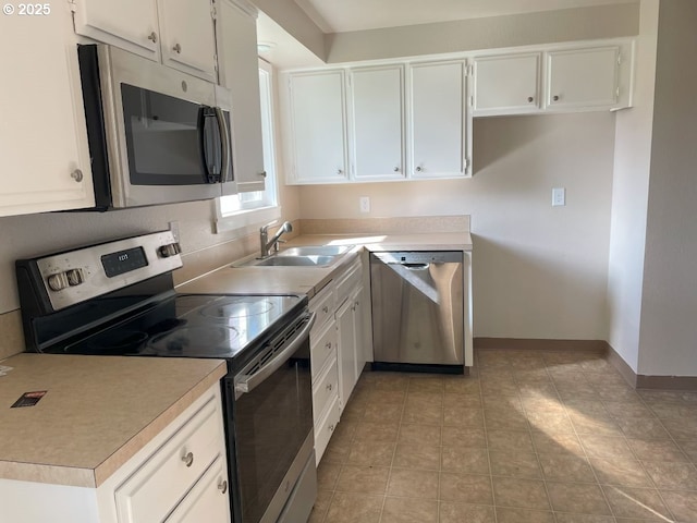 kitchen featuring white cabinets, baseboards, stainless steel appliances, and a sink