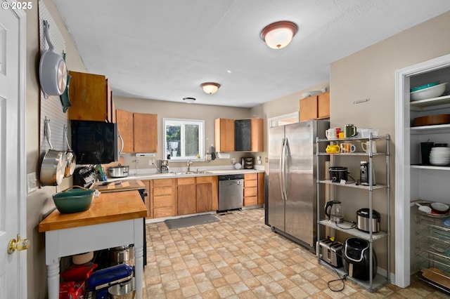 410 E D St, Rainier, OR 97048 - kitchen featuring appliances with stainless steel finishes, a sink, brown cabinetry, light flooring, and butcher block countertops