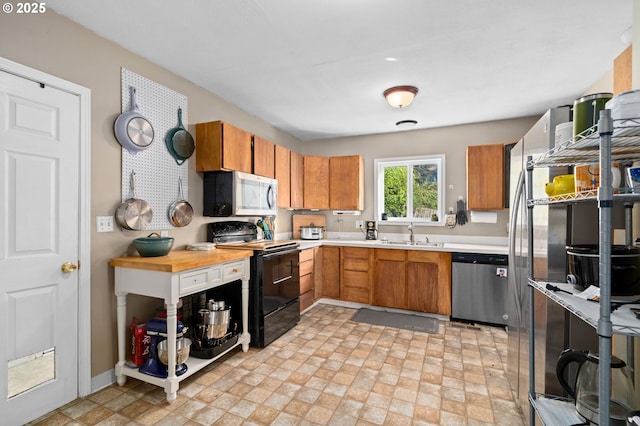 410 E D St, Rainier, OR 97048 - kitchen with appliances with stainless steel finishes, a sink, light countertops, brown cabinets, and baseboards