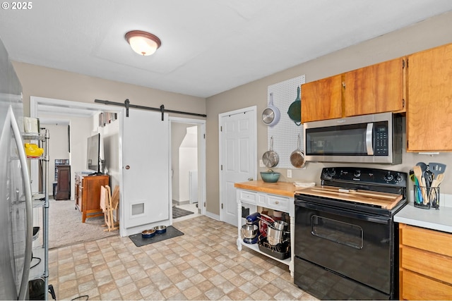 410 E D St, Rainier, OR 97048 - kitchen with stainless steel microwave, black range with electric stovetop, a barn door, light countertops, and light flooring