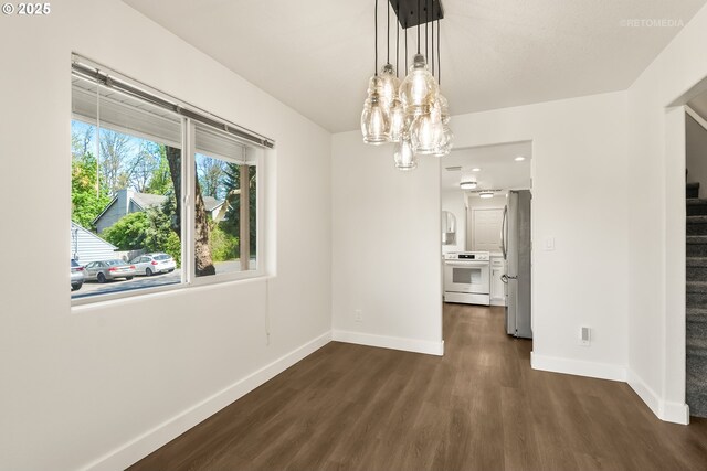unfurnished dining area featuring dark wood-type flooring, baseboards, a notable chandelier, and stairway