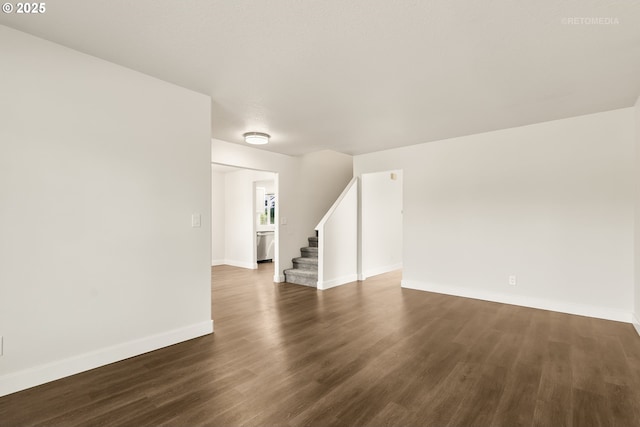 unfurnished living room featuring baseboards, stairs, and dark wood-style floors