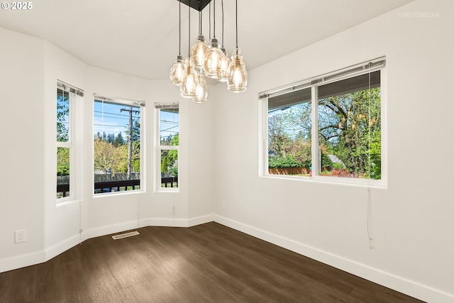 spare room with baseboards, visible vents, a chandelier, and dark wood-type flooring