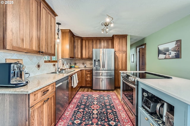 190 SE Shafford St, Estacada, OR 97023 - kitchen with stainless steel appliances, decorative backsplash, light wood-type flooring, brown cabinetry, and pendant lighting