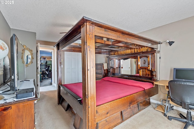 carpeted bedroom featuring a textured ceiling and a desk