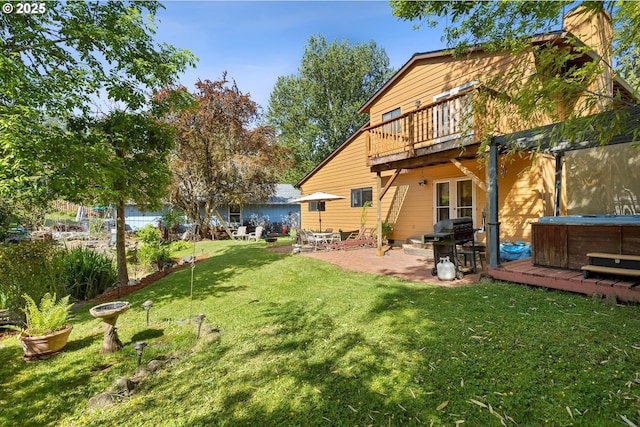 view of green lawn with a hot tub, a patio, and a deck