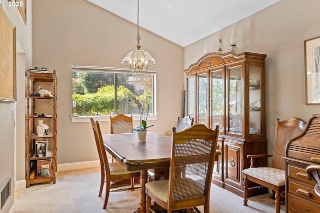 dining area with light colored carpet, a chandelier, high vaulted ceiling, and baseboards