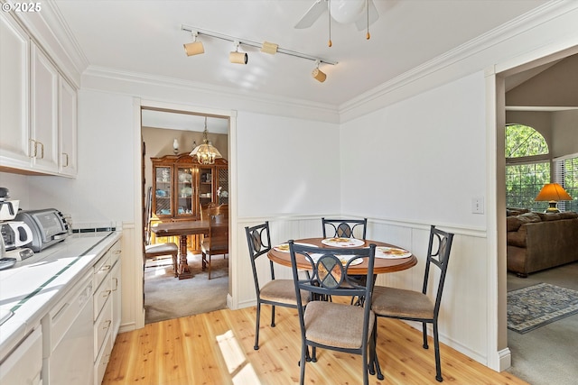 dining room with light wood-style flooring, track lighting, a wainscoted wall, ceiling fan, and crown molding