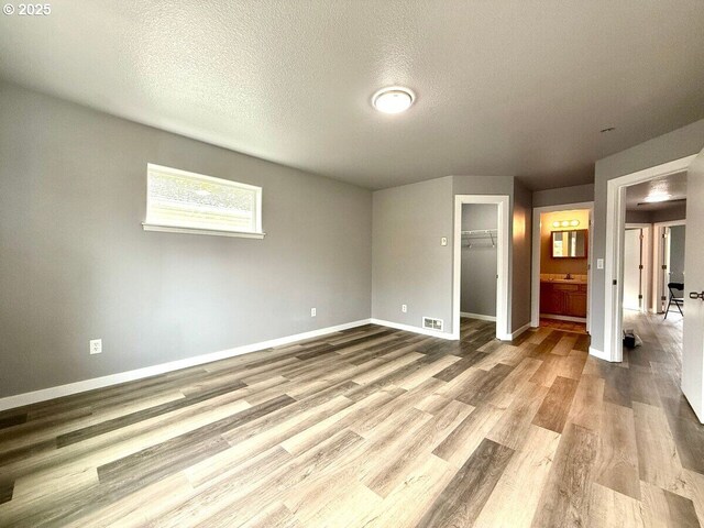 301 SE 129th Ave, Portland, OR 97233 - unfurnished bedroom featuring wood finished floors, baseboards, a textured ceiling, a spacious closet, and a closet