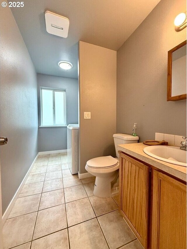 301 SE 129th Ave, Portland, OR 97233 - half bath with washer / dryer, tile patterned flooring, toilet, vanity, and baseboards