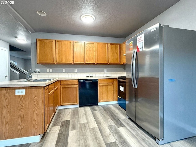 301 SE 129th Ave, Portland, OR 97233 - kitchen featuring freestanding refrigerator, black dishwasher, a sink, light wood-style flooring, and a peninsula
