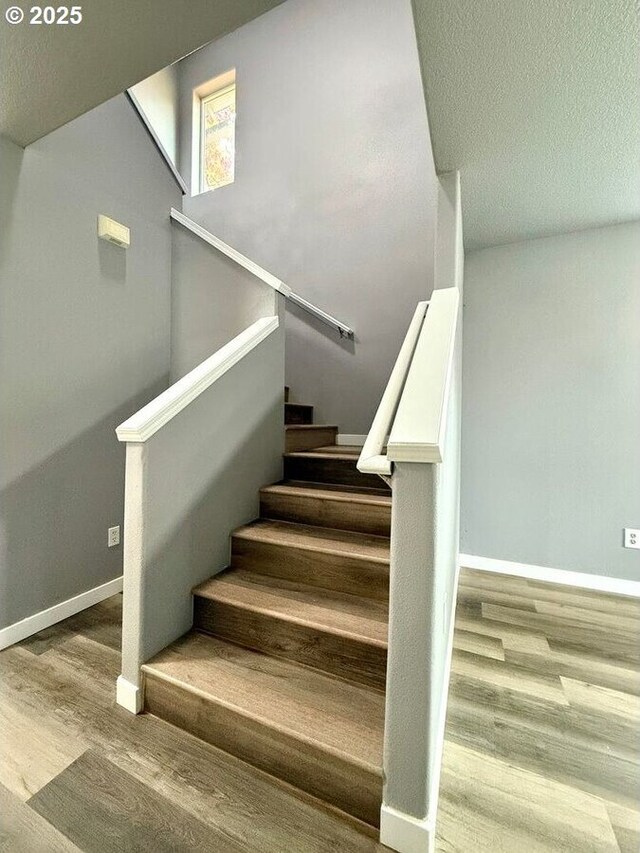 301 SE 129th Ave, Portland, OR 97233 - stairway featuring wood finished floors, a textured ceiling, and baseboards