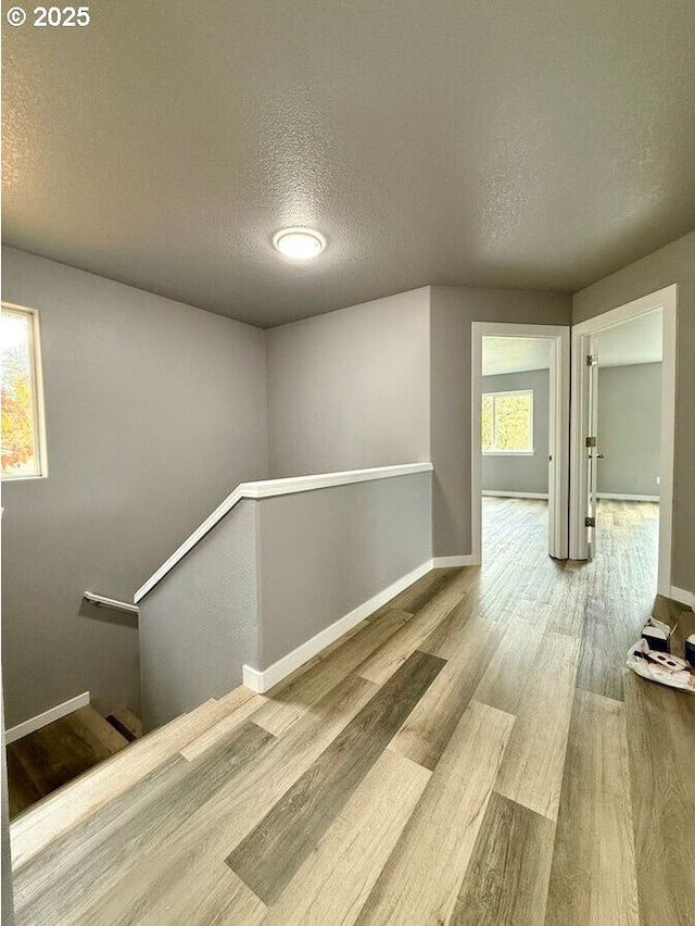 301 SE 129th Ave, Portland, OR 97233 - hall featuring an upstairs landing, a textured ceiling, wood finished floors, and baseboards