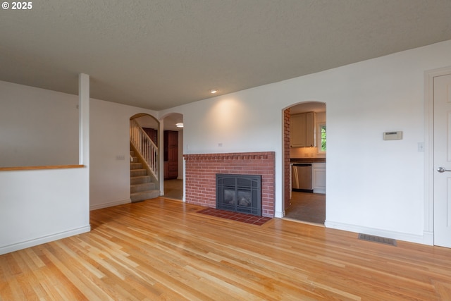 7105 Mississippi Dr, Vancouver, WA 98664 - unfurnished living room featuring light wood finished floors, a fireplace, baseboards, arched walkways, and recessed lighting