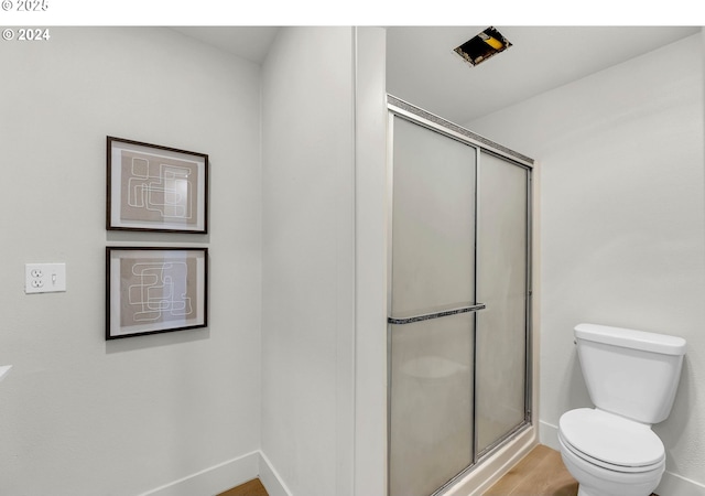 bathroom featuring hardwood / wood-style flooring, toilet, and a shower with shower door