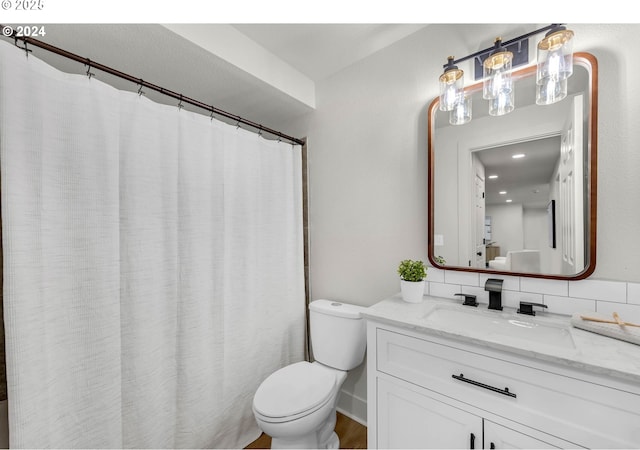 bathroom with vanity, backsplash, and toilet