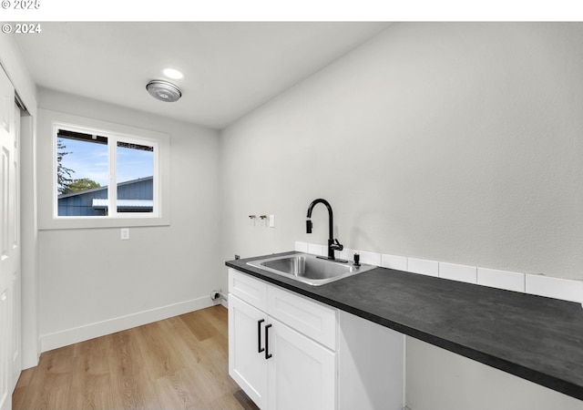 kitchen with white cabinetry, sink, and light hardwood / wood-style flooring